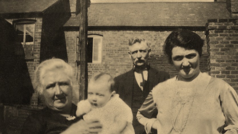 Four people outside a cottage, early 1900s